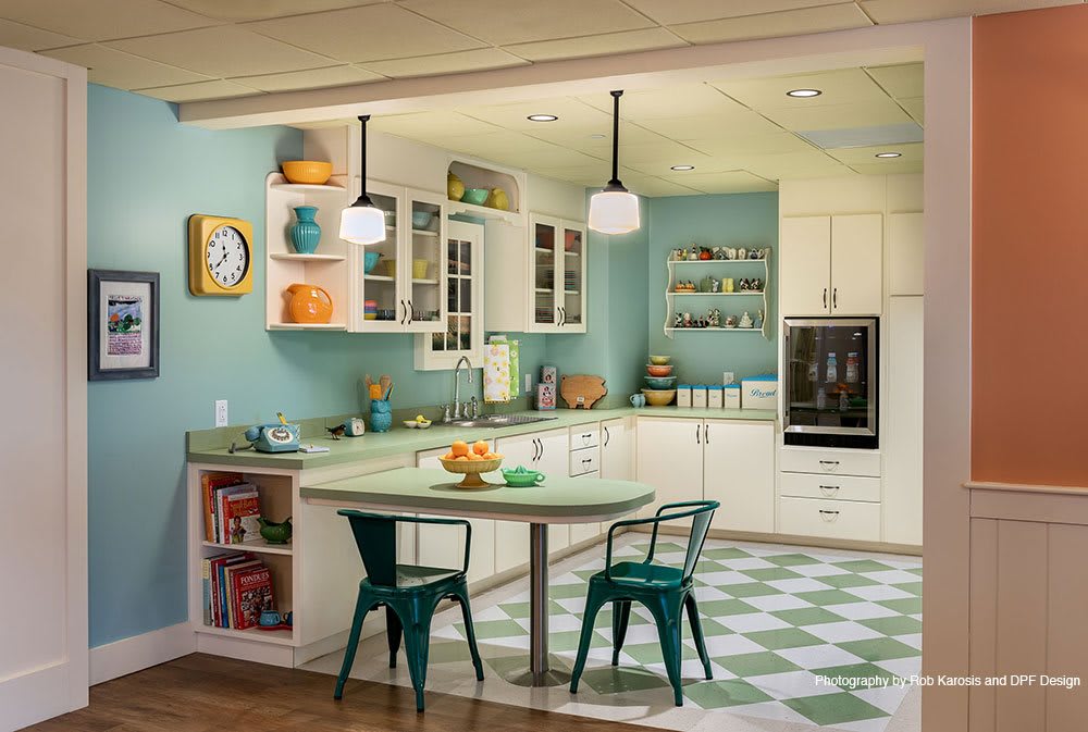 A retro-style kitchen with teal accents, open shelving, and a checkered floor.