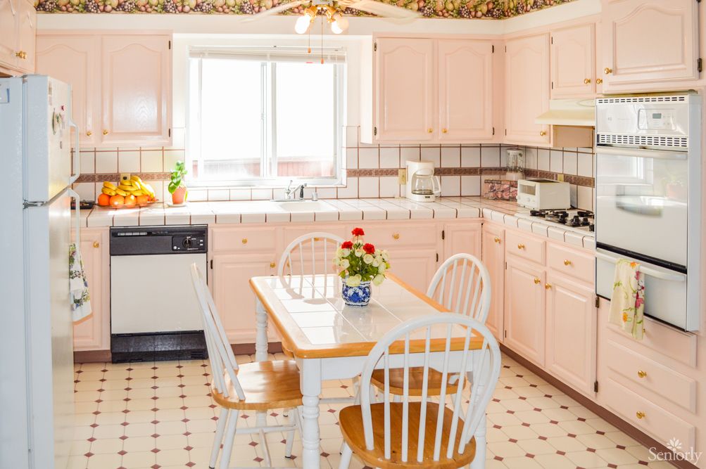 A retro kitchen with pink cabinets and a cozy dining area.
