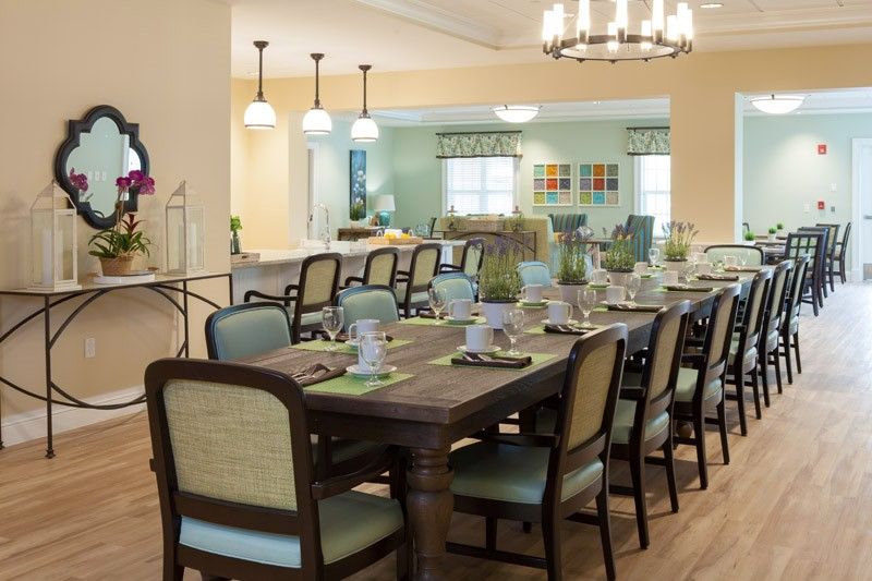 A spacious dining room with a large table set for a meal, featuring elegant lighting and comfortable seating.