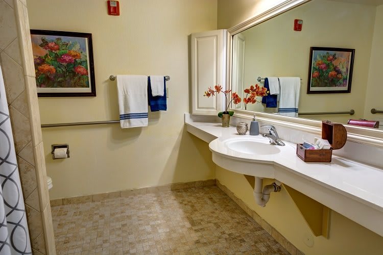 A well-organized bathroom with a large mirror, sink, towels, and decorative elements.