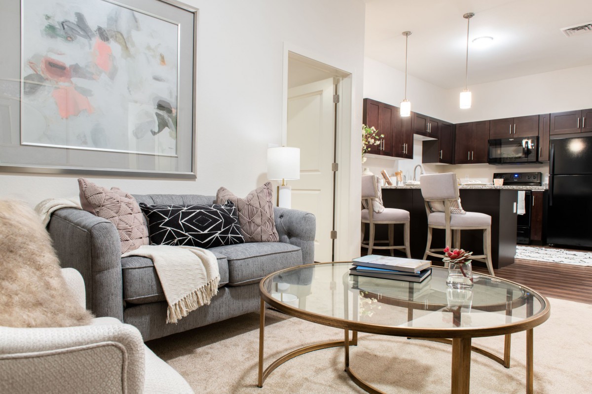A cozy living room with a comfortable sofa, stylish coffee table, and view into the kitchen area.