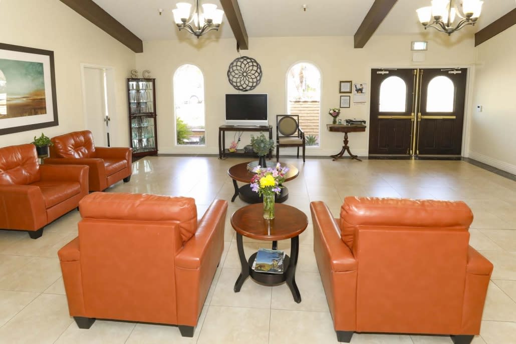 A modern living room with orange chairs, a central coffee table, and decorative elements.