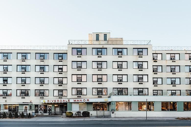 A view of a multi-story city hotel with numerous windows and a street-level entrance.