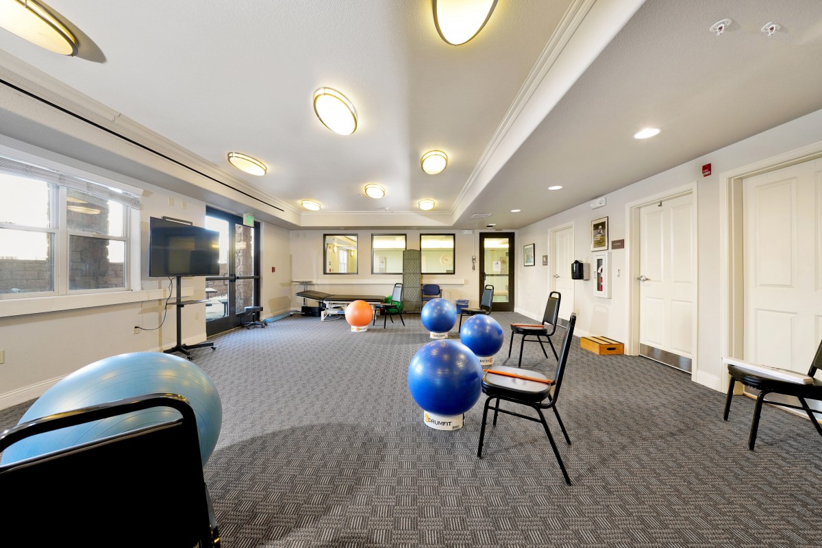 A well-lit fitness therapy room equipped with exercise balls and chairs.