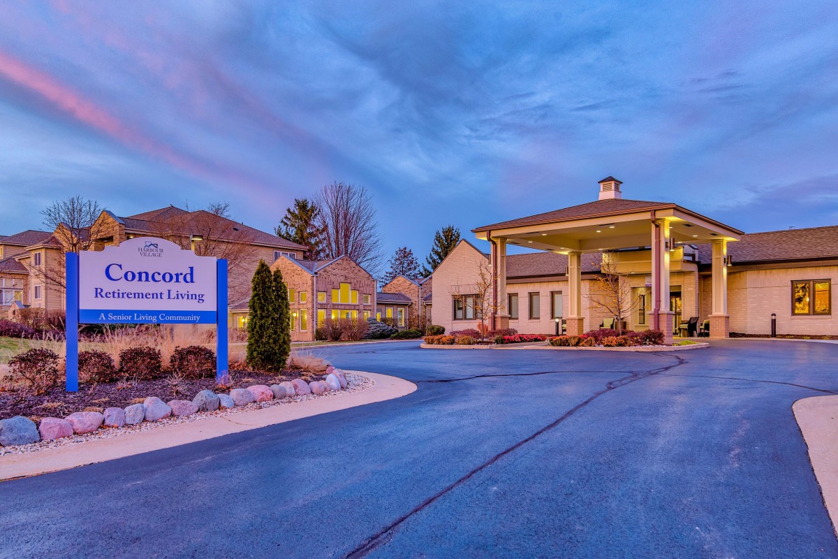 Entrance of a residential building with illuminated signage and driveway during the evening.