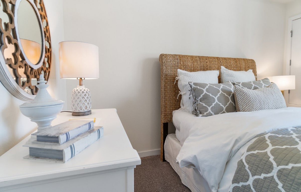A cozy bedroom setup featuring a bed with decorative pillows and a stylish lamp on the nightstand.