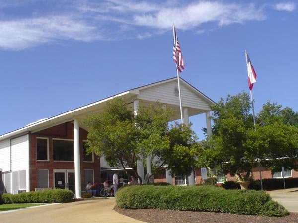 A modern building with an American and another flag, surrounded by trees under a clear sky.
