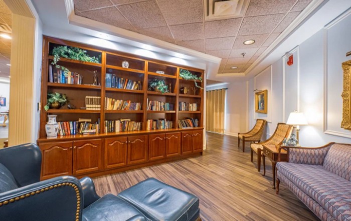 A cozy library space featuring a large wooden bookshelf and comfortable seating.