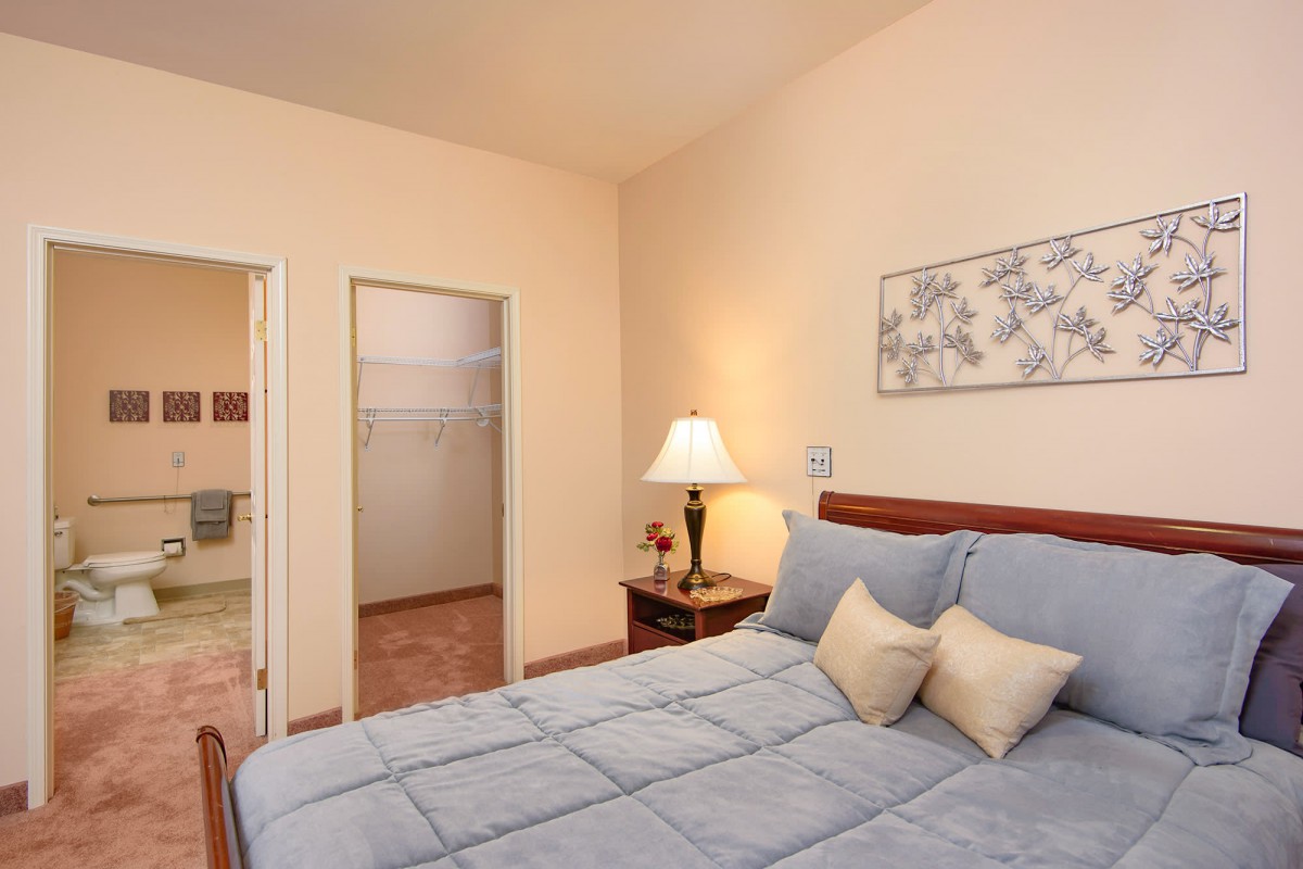 A cozy bedroom with a neatly made bed, bedside lamp, and decorative wall art.