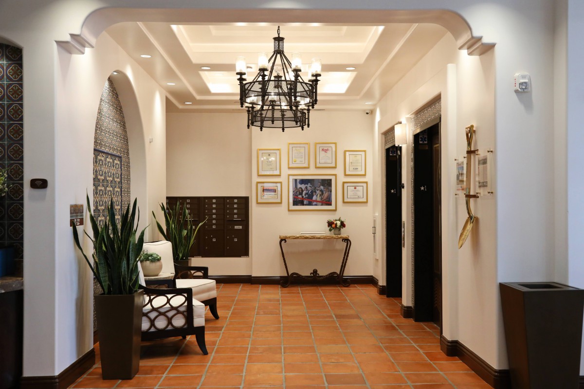 An elegantly designed lobby with classic decor features a chandelier, framed artwork, and comfortable seating.