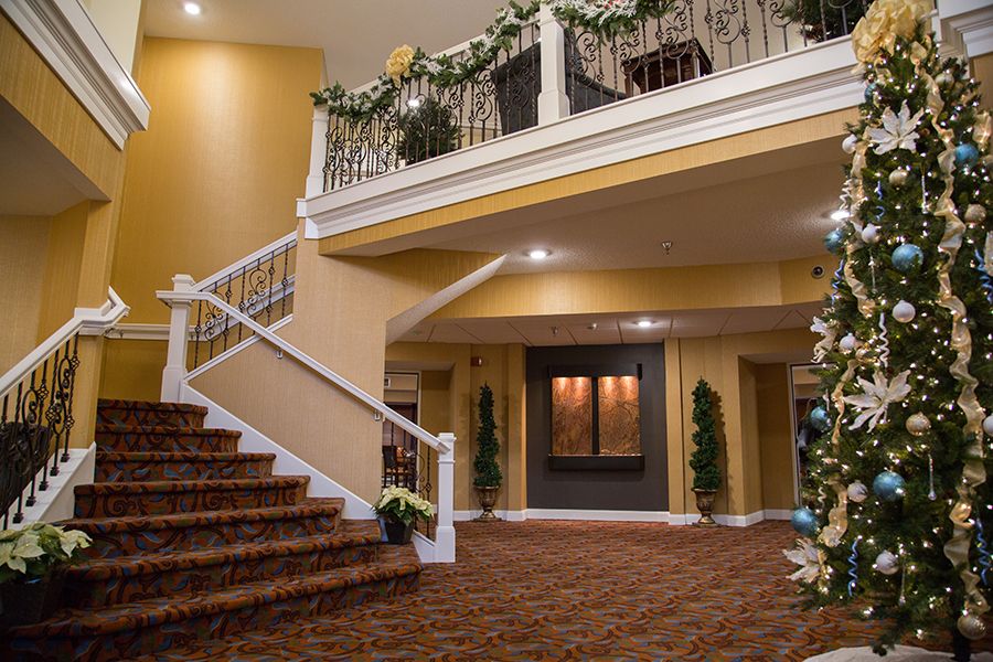 A warmly decorated interior features carpeted stairs and a balcony adorned with greenery.