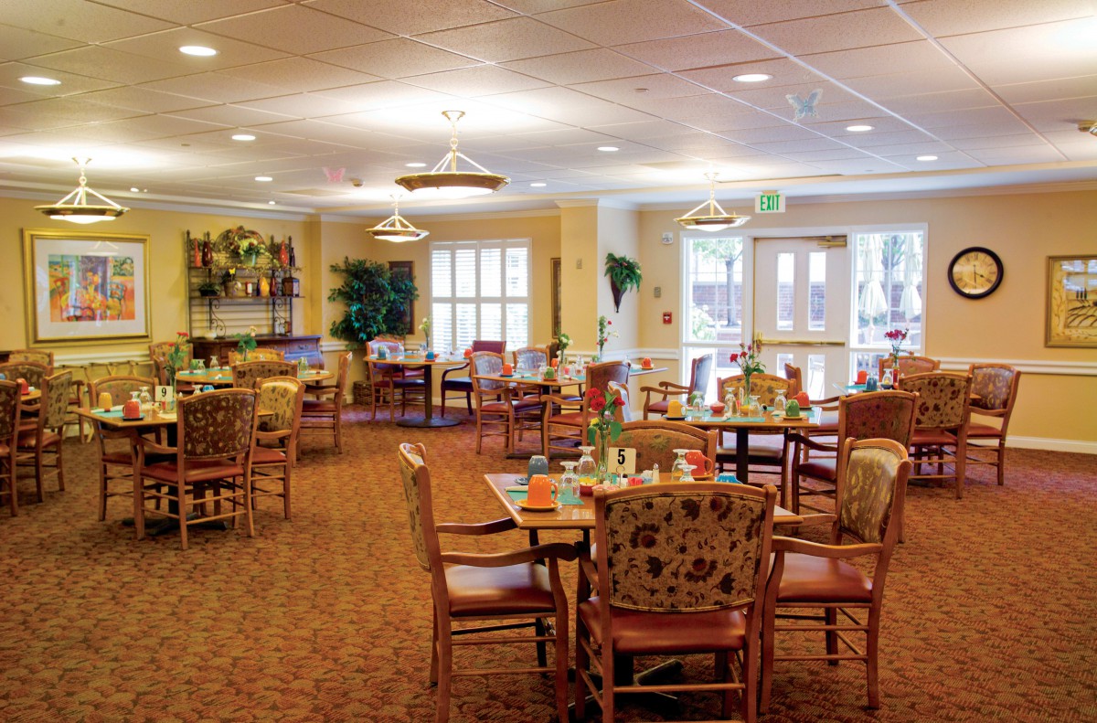 A cozy dining room interior with neatly arranged tables and chairs, warm lighting, and decorative elements.