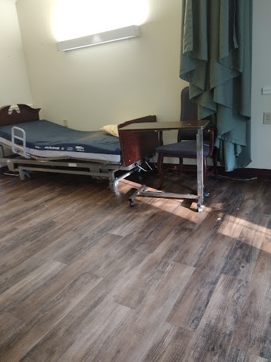 A hospital room featuring a bed, furniture, and natural light.