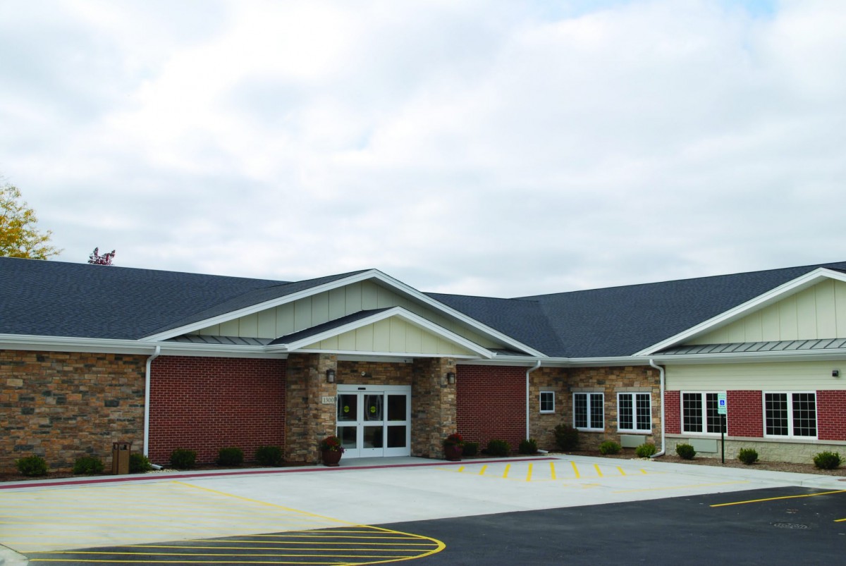 A modern building with a brick exterior and a spacious parking area.