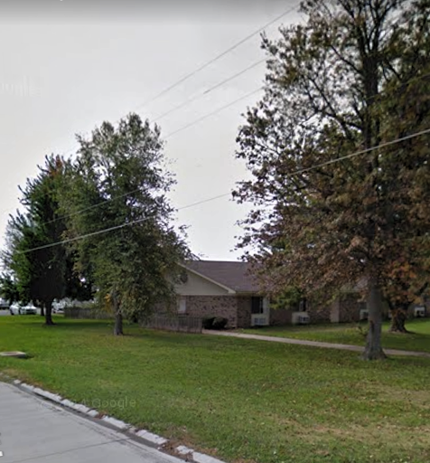 A quiet suburban house surrounded by trees and a well-kept lawn.