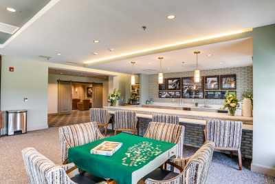 A modern lounge area featuring a table with a puzzle, surrounded by striped chairs and illuminated by stylish lighting.