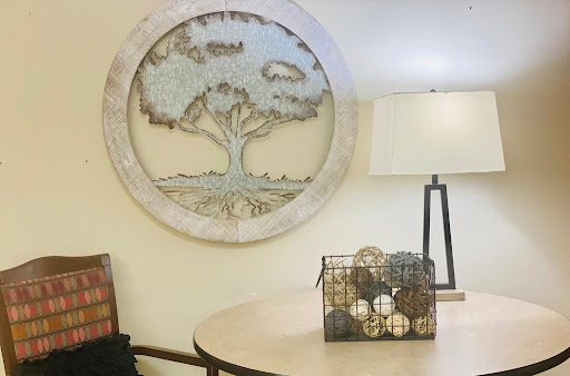 A beautifully designed wall art featuring a tree, complemented by a stylish lamp and decorative items on the table.