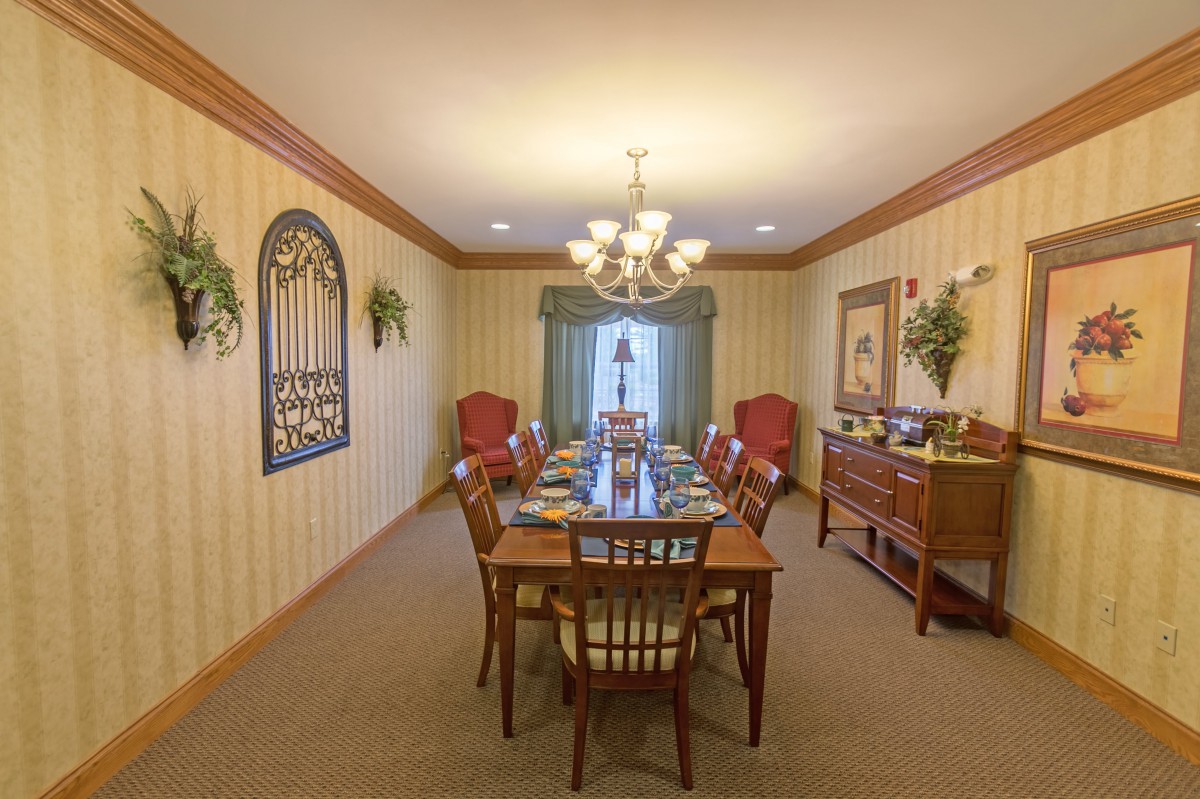 A traditional dining room with a large wooden table, surrounded by chairs and lit by an elegant chandelier.