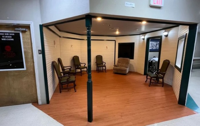 An indoor room with several chairs arranged in a semi-circle on a wooden floor.