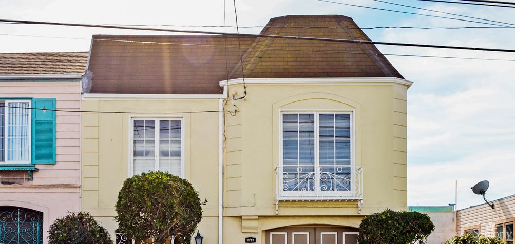 A residential house with a sloped roof and large windows above a garage.