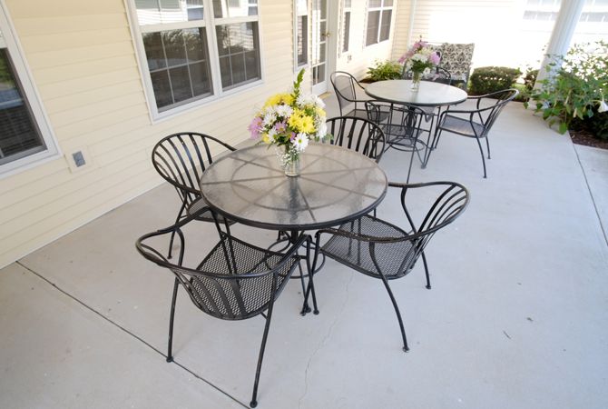 Outdoor patio with metal tables and chairs, adorned with floral centerpieces.
