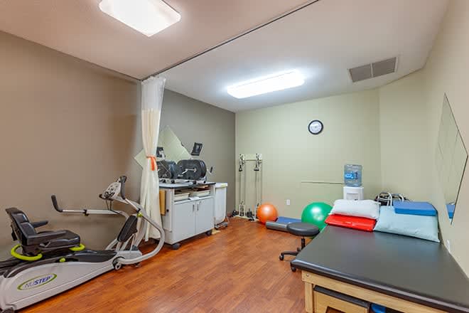 A physical therapy clinic with exercise equipment and treatment tables.