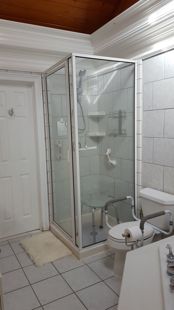 A modern bathroom with a glass-enclosed shower, toilet, and sink.