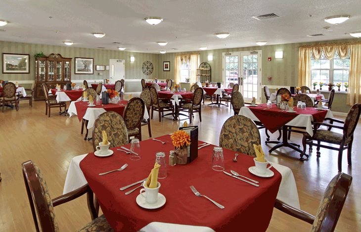 An elegantly decorated dining room with red table settings and neatly arranged chairs.