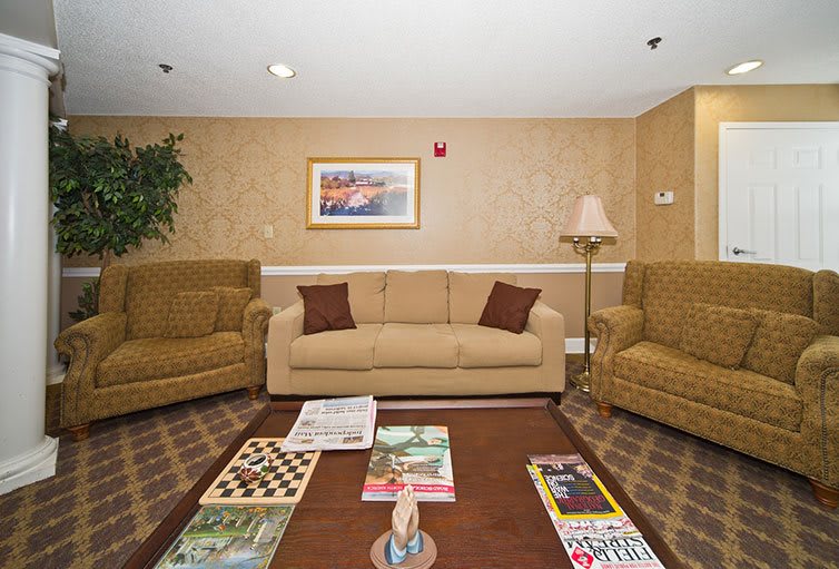 A cozy living room with a sofa, armchairs, and a coffee table displaying magazines and a chessboard.