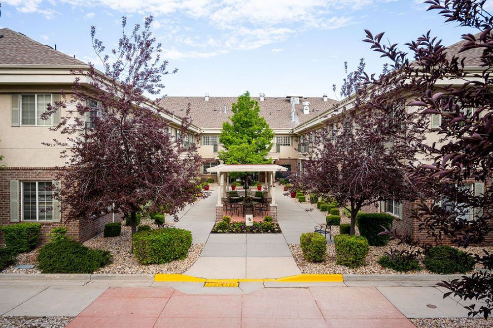 A well-maintained courtyard with a central walkway, surrounded by neatly trimmed bushes and trees.