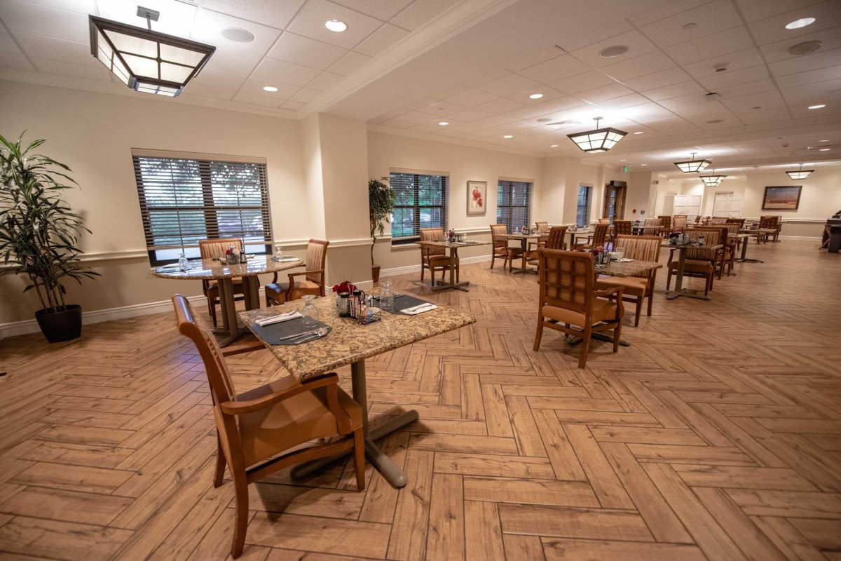 A spacious and elegantly decorated dining area with wooden floors and well-arranged tables.