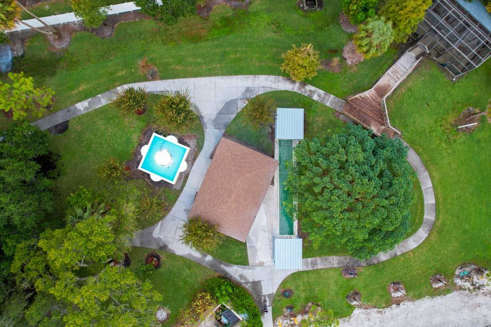 Aerial view of a property featuring a house, swimming pool, and landscaped garden.