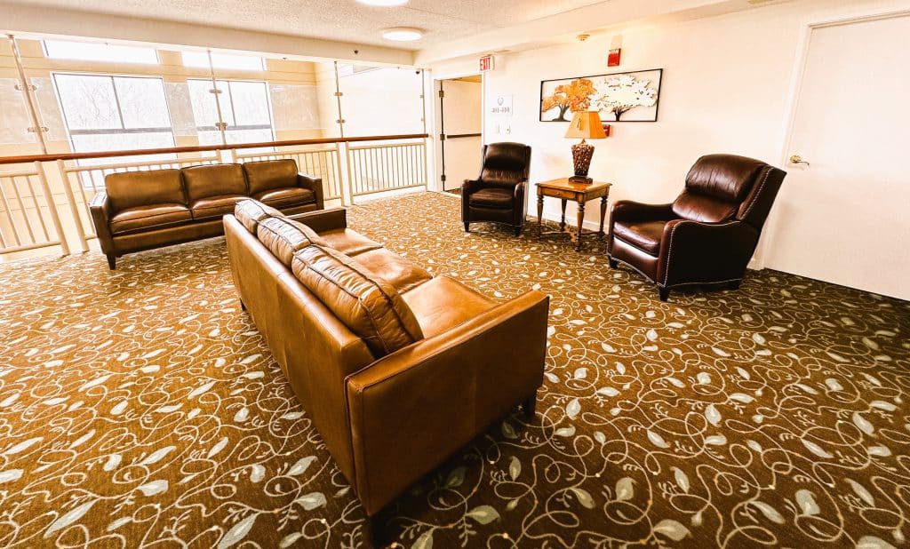 A cozy lobby seating area with leather sofas, armchairs, and warm lighting.