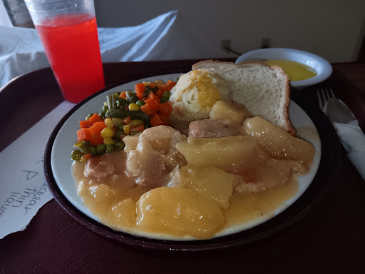 A hearty meal featuring chicken with a savory sauce, mixed vegetables, and bread.