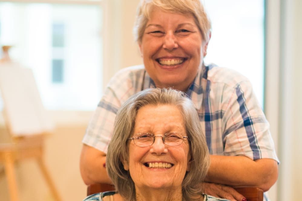 Two elderly women smiling indoors, reflecting friendship and joy.