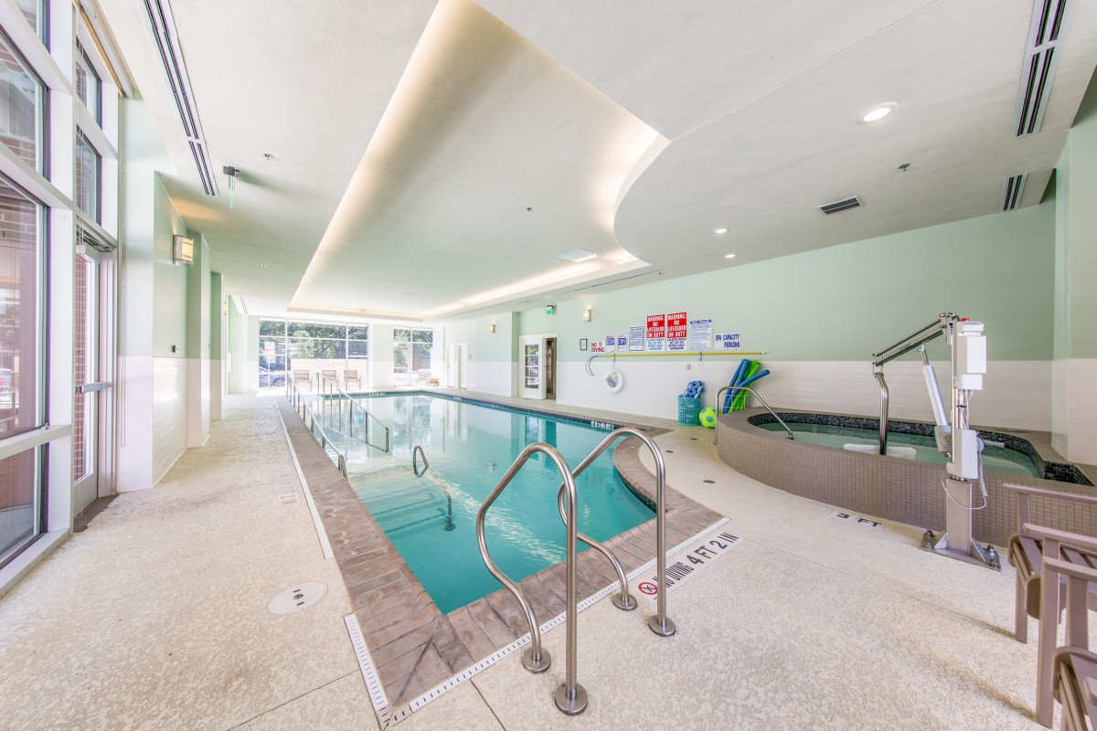 A modern indoor swimming pool with bright lighting and tiled flooring.