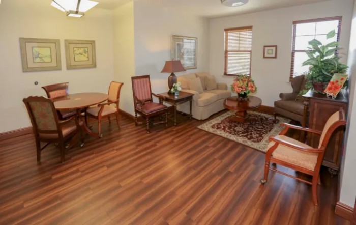 A cozy living room with hardwood floors, featuring a sofa and chairs around a coffee table.
