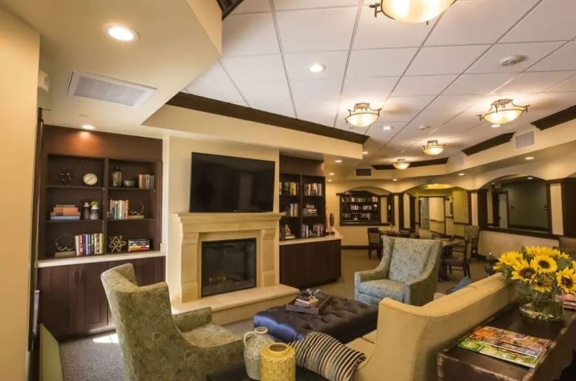 A cozy living room with comfortable seating, a fireplace, and bookshelves.