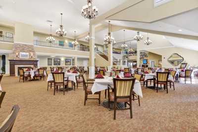 A spacious and elegant dining area with chandeliers and neatly arranged tables and chairs.