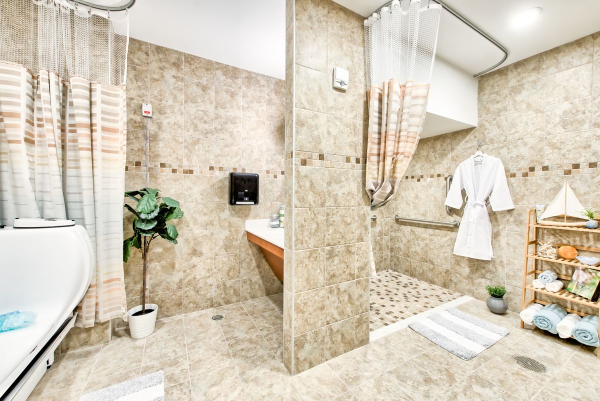 A modern bathroom featuring a tiled shower area, sink, and decorative plant.