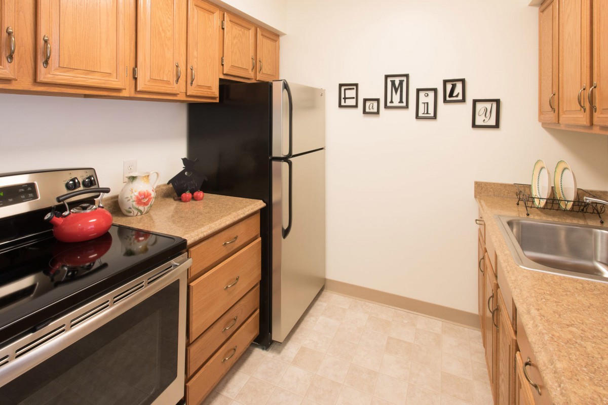 A modern kitchen with wooden cabinets, stainless steel appliances, and a neatly arranged countertop.