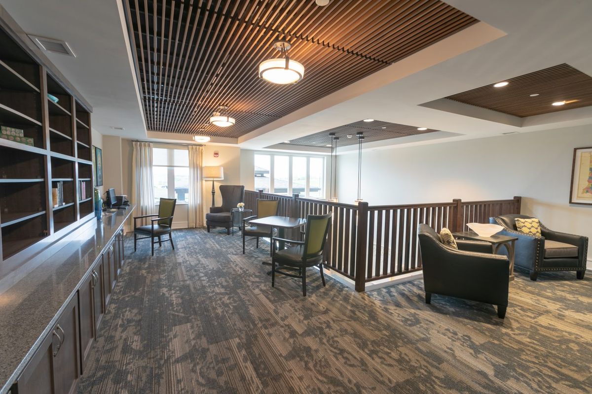 A modern lounge area featuring a wooden ceiling, comfortable seating, and tables.