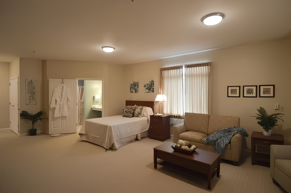A cozy bedroom with a bed, sofa, and warm lighting.