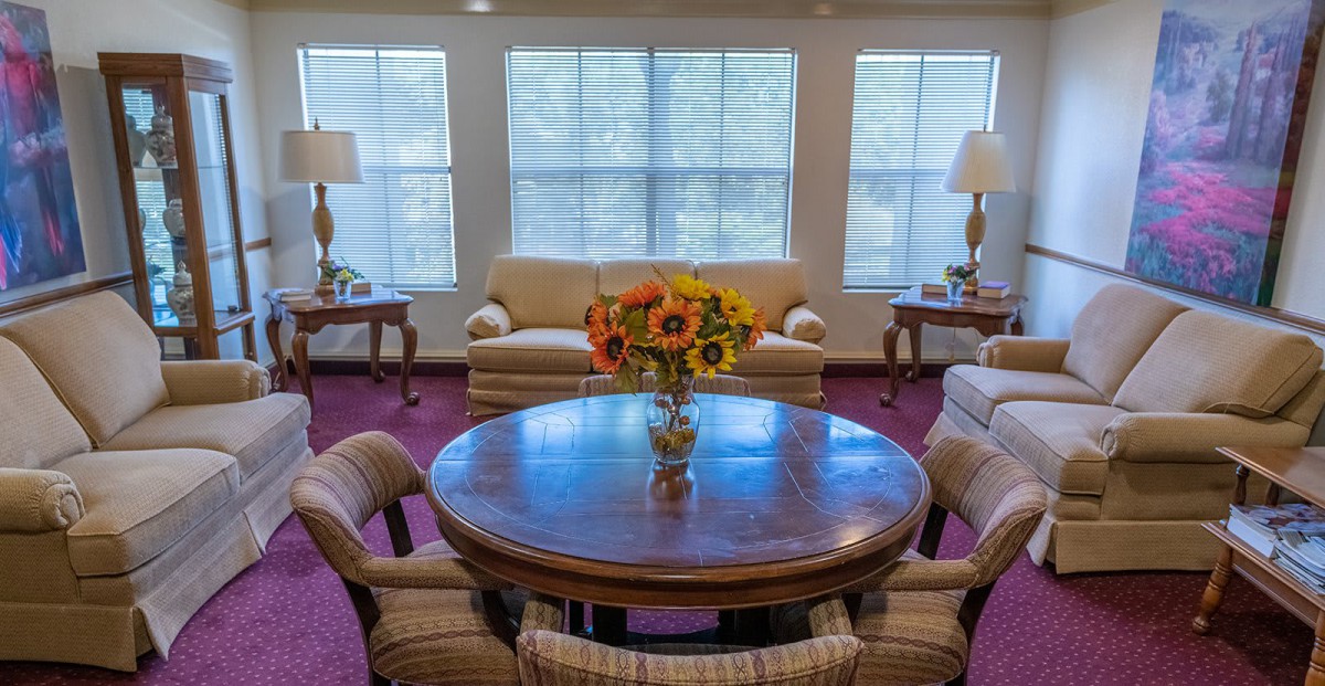 A cozy living room with a round wooden table, floral centerpiece, and comfortable sofas.