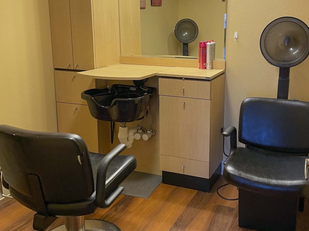 A hairdresser's station in a salon, featuring a chair, sink, and mirror.