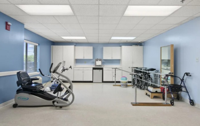 A well-equipped physical therapy room with exercise machines and parallel bars.