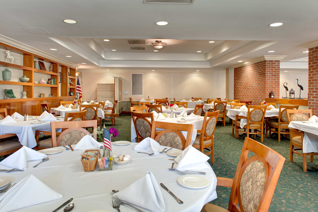 An elegant restaurant dining room with neatly set tables and white tablecloths.
