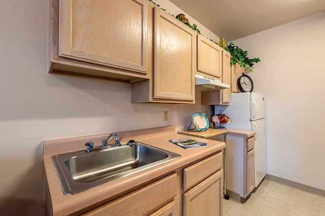 A compact kitchen setup featuring wooden cabinets, a sink, and appliances.