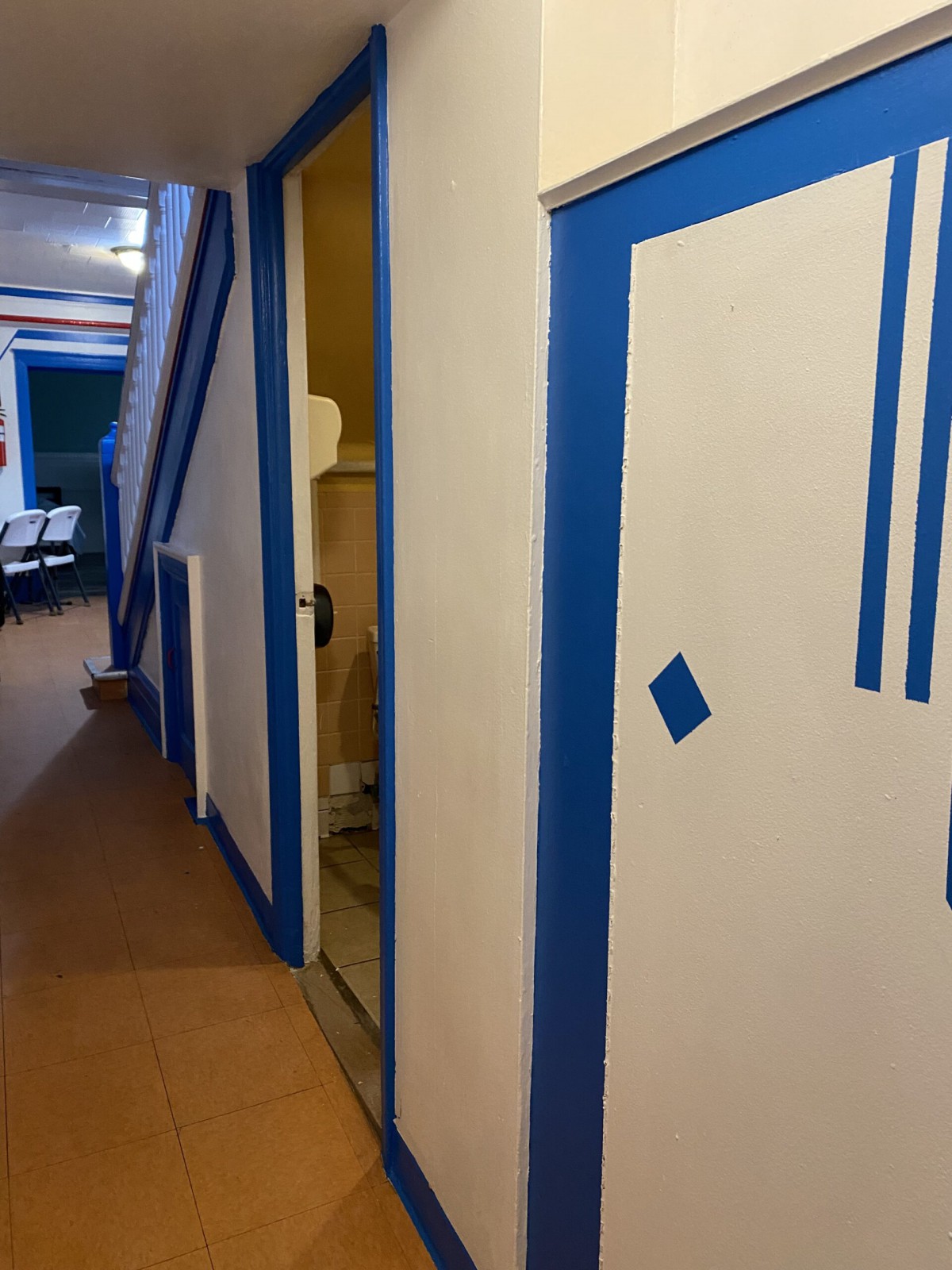 A hallway under renovation with blue tape outlining doors and walls.