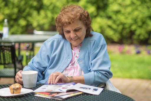An elderly woman enjoying a peaceful moment outdoors while reading a magazine.